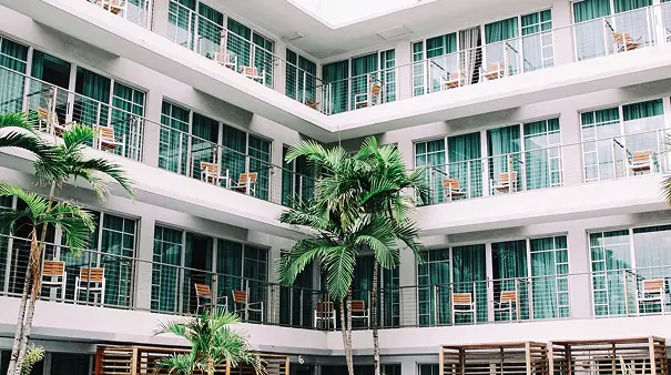 A building with many windows and palm trees in the center.