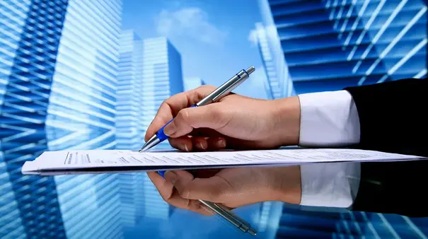 A person writing on paper with pen and ruler.